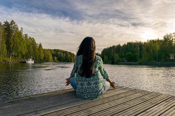 Femme qui regarde un lac en position yoga.